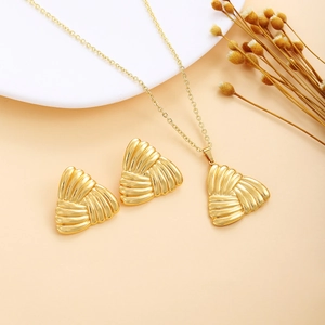 Macro detail of golden seashell necklace and earrings set with relief stripes