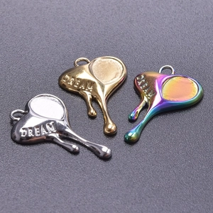 Detailed view of melting heart pendants in silver, gold, and rainbow finish with DREAM engraving