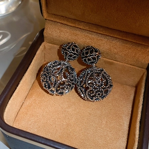 Detailed close-up of vintage hollow silver earrings with textured spheres in a jewelry box
