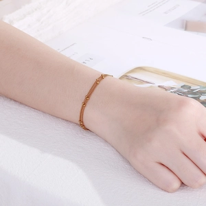 Minimalist double-layered gold bead chain bracelet for women on textured background