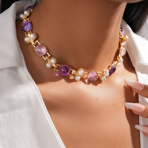Vintage gold necklace featuring purple resin gems and white pearls on a model