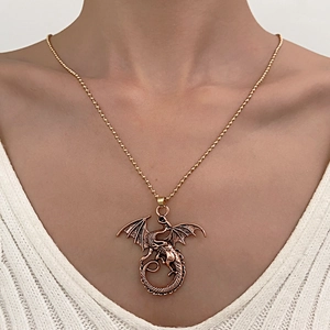 Detailed view of a vintage bronze dragon pendant necklace worn on a white knitted sweater