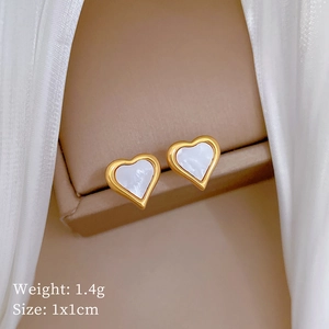 Macro detail of heart-shaped clover stud earrings with white shell inlay in gold frame