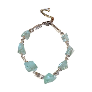 Irregular green gemstone beaded bracelet with silver metal spacers on a white background