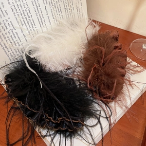 Detailed close-up of acrylic feather hair clips in black, white, and brown on a book