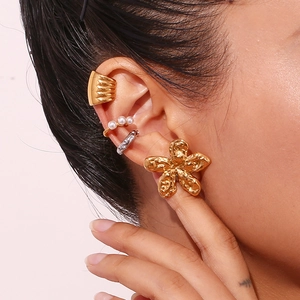 Macro shot of 18K gold-plated geometric earrings and pearl ear cuffs on a model