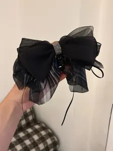 Detail of black chiffon bow hair claw clip with sparkling rhinestone embellishment