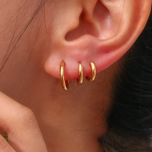 Close-up of three graduated 18K gold plated stainless steel hoop earrings on ear