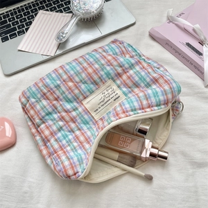 Detailed top view of quilted checkered cosmetic bag with metal zipper and makeup items
