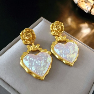 Détail de boucles d'oreilles vintage cœur doré avec reflets irisés sur boîte à bijoux