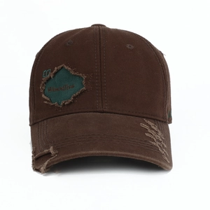 Detailed view of distressed brown canvas baseball cap with 07 embroidery and frayed holes