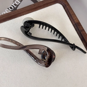 Detail view of glossy black and transparent brown hair clips on a minimalist tray