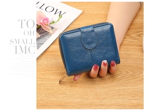 Close-up of deep blue leather short wallet for women featuring metal zipper on wooden desk