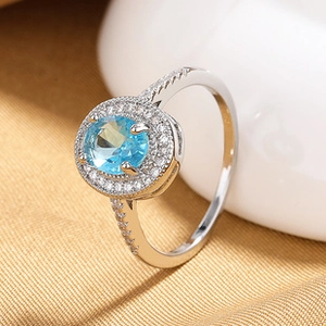 Macro view of a silver ring featuring a blue oval gemstone and sparkling zircon accents