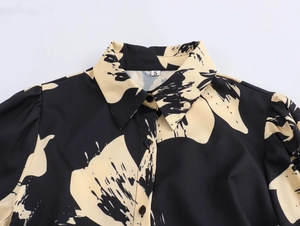 Macro shot of shirt collar with black buttons and beige floral print on black fabric
