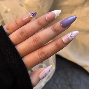 Detailansicht von mandelförmigen Press-on-Nägeln mit 3D-Blumen und violetten Mustern