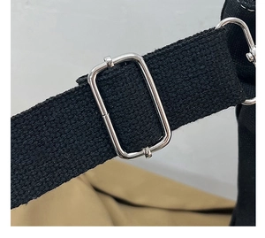 Detailed view of the black canvas strap and adjustable silver metal buckle on the bag