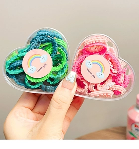 Pink and green elastic hair ties stored in heart-shaped boxes with Thank You stickers
