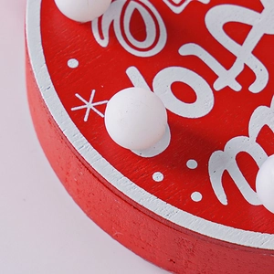 Macro shot of red wooden holiday LED ornament with white Merry Holiday lettering