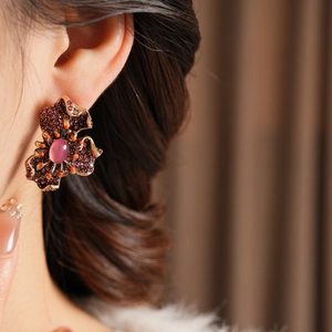 Gros plan de boucles d'oreilles fleurs vintage avec cristaux violets et pierre centrale