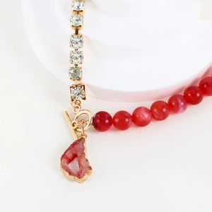 Detail der Goldkette mit roten Marmorperlen, Strasssteinen und rosa Kristallanhänger