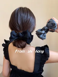 Dettaglio di eleganti fermagli per capelli con fiocco in tessuto nero e grigio melange