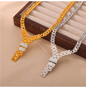 Detail of gold and silver Y-shaped necklaces with honeycomb texture and zircon on wood box