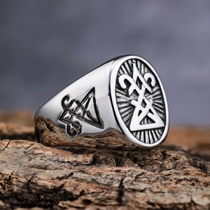 Polished stainless steel signet ring with engraved mystical symbols on wood surface