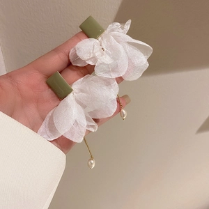 Detail view of long floral earrings with white organza petals and a green resin stud