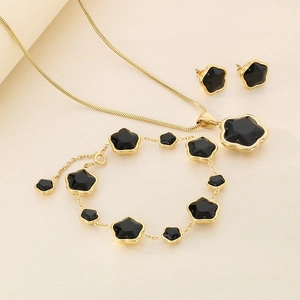 Detailed set of gold clover jewelry with black glass stones and elegant long tassels