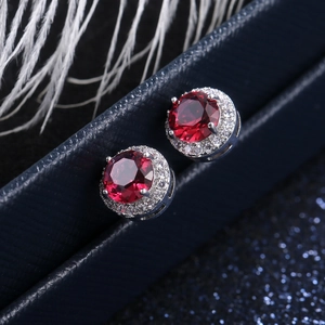 Macro detail of round red zircon halo earrings with silver setting on a gift box
