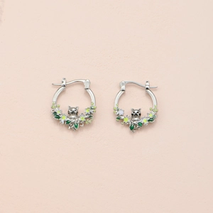 Detail of silver huggie hoop earrings with enamel raccoon and floral charms