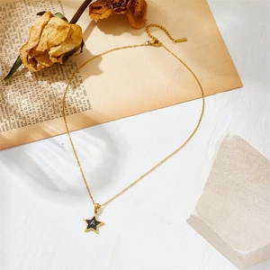 Gold star necklace with black enamel letter A pendant on a vintage aesthetic background