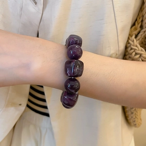 Détail du bracelet en perles d'acrylique marbré violet foncé sur le poignet d'une femme