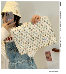 Close-up of quilted floral laptop sleeve held by a model in casual denim outfit
