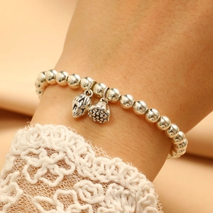 Detailed close-up of a silver beaded bracelet with lotus seed charms on a lace wrist