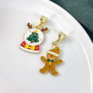 Detail of Christmas earrings featuring a festive gingerbread man and a snowflake crystal ball