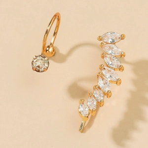 Macro detail of gold asymmetric stud earrings with marquise-cut cubic zirconia crystals