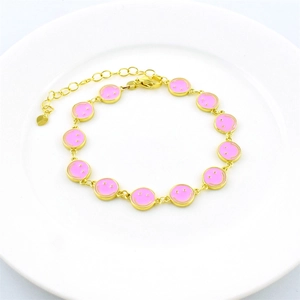 Gold plated link bracelet featuring pink enamel smiley face charms on a white plate