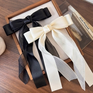 Set di grandi fiocchi per capelli in chiffon nero e beige su un vassoio di legno