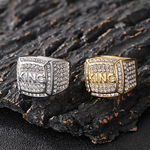 Close-up of gold and silver hip hop KING rings with square iced out crystals on rock