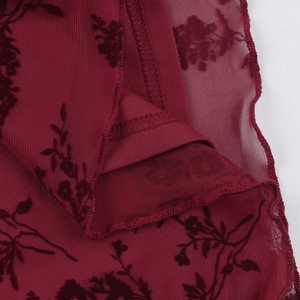 Macro detail of wine red velvet floral embroidery on semi-transparent mesh fabric