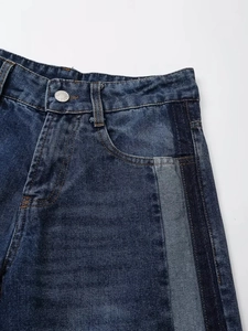Detailansicht der dunkelblauen Jeans mit seitlichen Kontrasteinsätzen und Metallknopf
