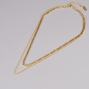 Detail of gold double-layered necklace showing Figaro chain and K18 hallmark tag