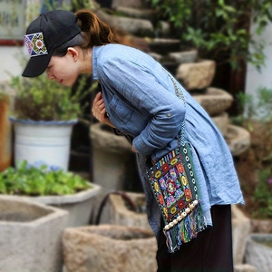 Close-up of bohemian embroidered crossbody bag with tassels and matching ethnic baseball cap