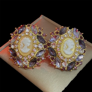 Detail of vintage cameo stud earrings with purple marquise and white round rhinestones