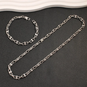 Detailed view of silver stainless steel necklace and bracelet set with cross link design