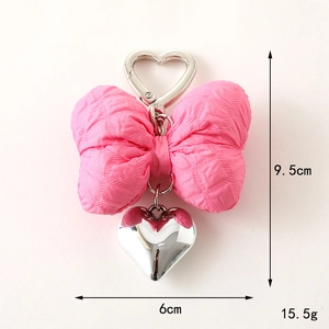 Pink fabric bow keychain with silver metal heart pendant measuring 9.5cm in height