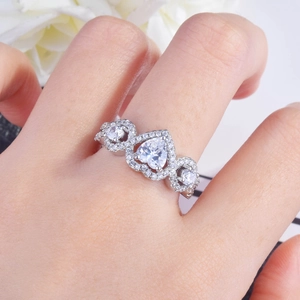 Sparkling silver heart-shaped halo engagement ring with pavé diamonds on model's finger