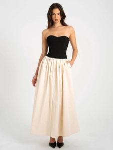 Détail d'une robe bustier bicolore avec corsage noir et jupe longue plissée ivoire élégante
